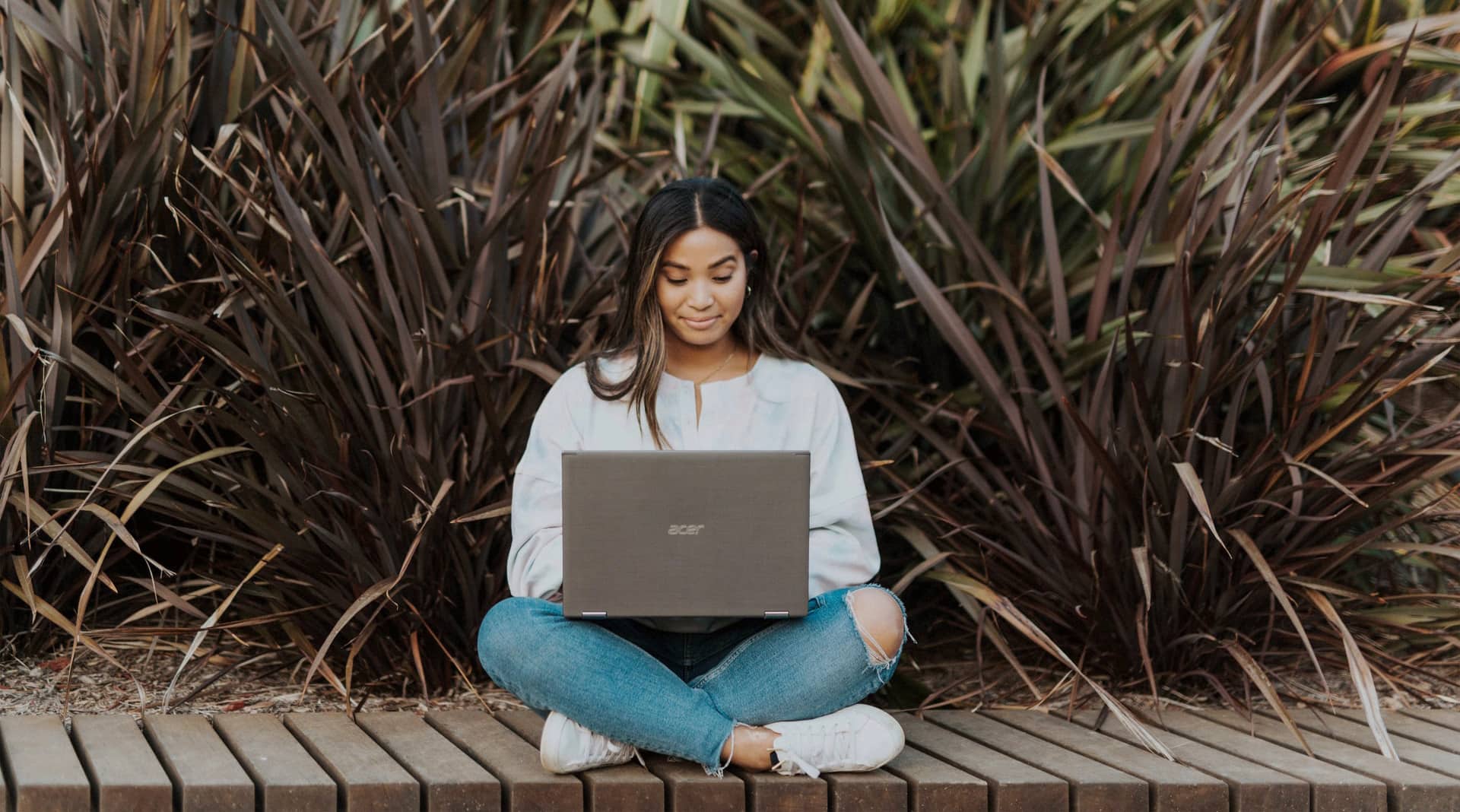 A student on her laptop with plants behind her